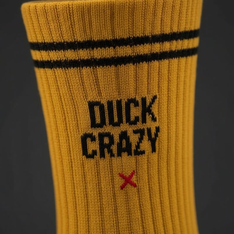 Macro close-up of the Duck Crazy lettering knitted into the sock cuff